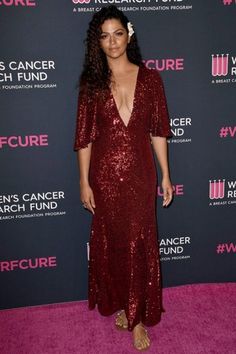 a woman in a red dress standing on a pink carpet