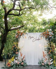 an outdoor wedding ceremony with flowers and greenery on the back wall that says ann's chapel