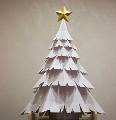 an origami christmas tree with a gold star on top is shown in front of a gray background