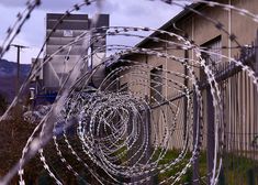 barbed wire on the side of a building with mountains in the background