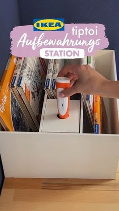 a person is holding an orange and white device in a drawer with magazines on it