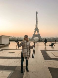 a woman is standing in front of the eiffel tower with her umbrella up