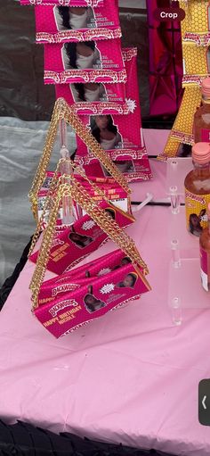 the table is set up with pink and gold candy boxes, jars, and other decorative items