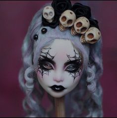 a doll with skulls on her head and makeup is holding a stick in front of her face