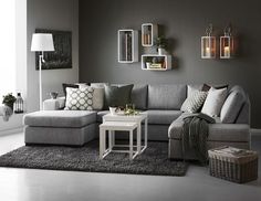 a living room with grey walls and white flooring, gray couches, black rugs and pictures on the wall