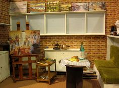 a living room filled with furniture next to a brick wall covered in pictures and paintings