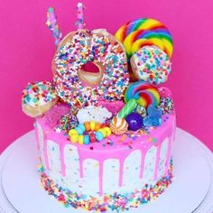 a birthday cake decorated with sprinkles, donuts and rainbow candies