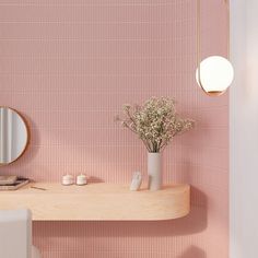 a bathroom with pink tiles and a wooden shelf holding a vase filled with baby's breath flowers