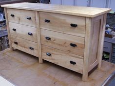 a wooden dresser sitting on top of a piece of plywood in a workshop area