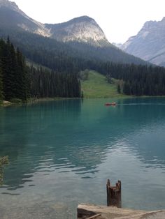 there is a boat that is in the water near some mountains and trees on the shore