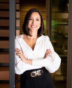 a woman standing with her arms crossed in front of a door and looking at the camera