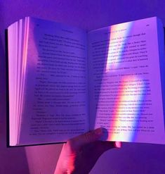 a person holding an open book in their left hand with the light shining through it