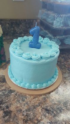 a blue frosted cake with the number one on it sitting on a counter top