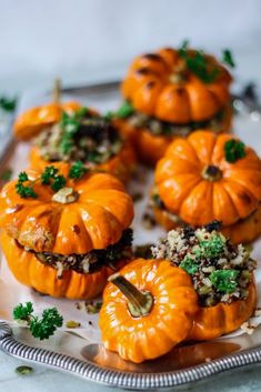 several mini pumpkins are sitting on a plate with parsley and other things around them