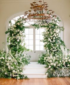 an archway decorated with white flowers and greenery