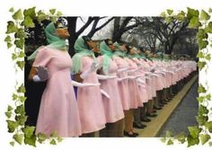 a group of women dressed in pink dresses and green headscarves are lined up