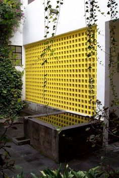 an outdoor area with a yellow screen and some plants on the side of the building