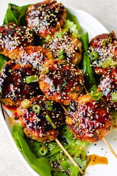 chicken skewers covered in sesame seeds and garnished with sauce on a white plate