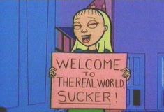 a woman holding a sign that says welcome to the real world suckerr