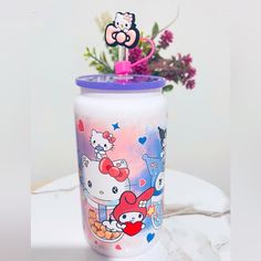 the hello kitty tumbler is next to a vase with flowers