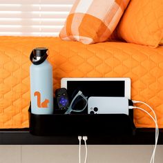 an orange bedspread is next to a blue water bottle and cell phone on a black tray