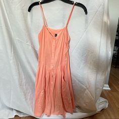 Never Worn Peach Color Dress With Adjustable Straps. Buttons Down The Middle And Deep Pockets. Peach Sleeveless Sundress For Day Out, Spring Peach Sundress For The Beach, Spring Peach Sundress For Beach, Spring Peach Beach Sundress, Casual Peach Sleeveless Sundress, Summer Peach Mini Dress For Day Out, Peach Sundress For Spring, Peach Sundress Mini Dress For Summer, Peach Sundress For Summer