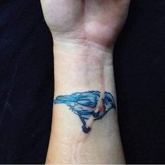 a wrist tattoo with a blue bird on it