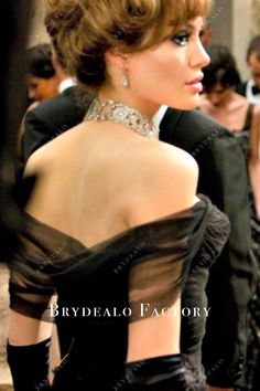 the back of a woman in a black dress with sheer neckline and cuffs on