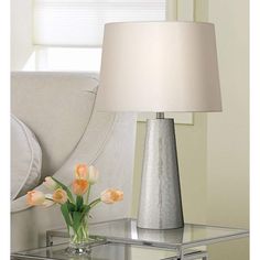 a vase with flowers on a table next to a lamp and couch in a living room