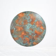 a round metal plate sitting on top of a white table covered in orange and blue paint