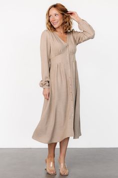 Casual and stylish all in one dress Lightweight linen-like material Neutral taupe color V-neckline Buttoned placard down front of dress Gathering at bust, shoulder yoke, and across back Long sleeves with single buttons at cuffs Upturned, paneled V-waistband with subtle gathering underneath Elastic at back waist Unlined 63% Recycled Polyester, 37% Polyester Marianne is 5'6, cup size 34D, size 6 and wearing size S Fall Linen Midi Dress For Brunch, Neutral Dresses With Button Closure For Daywear, Neutral Dress With Button Closure For Daywear, Beige Linen Dress For Fall, Beige Linen Fall Dress, Chic Neutral Dresses With Buttons, V-neck Midi Dress With Button Closure For Brunch, Neutral Daywear Dress With Buttons, V-neck Neutral Dress For Brunch