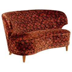 an orange and brown floral couch with wooden legs