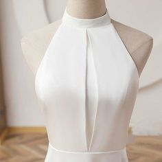 a white dress on a mannequin with a halter neck and pleated skirt