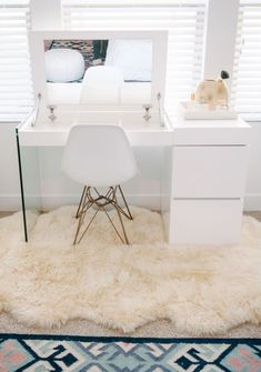 a white desk with a mirror, chair and purse on top of it in front of a window