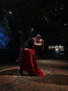 a woman in a red dress is kissing a man in a black suit and tie