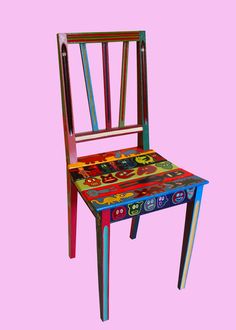 a colorful wooden chair sitting on top of a pink background