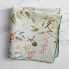 two napkins with floral designs on them sitting on a marble countertop next to each other