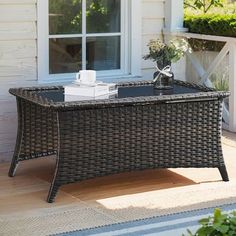 a wicker coffee table sitting on top of a wooden floor next to a window