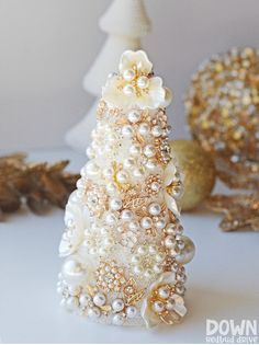 a christmas tree made out of pearls and other ornaments on a white table with gold balls