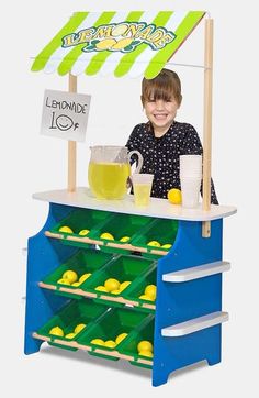 a young boy standing behind a lemonade stand