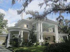 a large white house with trees and bushes around it