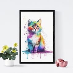 a colorful cat sitting on top of a table next to a vase with flowers in it