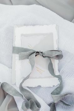 a piece of paper with a ribbon tied around it on top of a white blanket