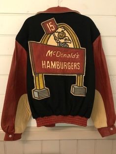 I am offering this extremely rare McDonald's promotional Varsity jacket, crafted in Leather and Wool by designer Jeff Hamilton, and featuring the first Maccas advertising slogan with the Speedee character and a single Golden Arch. Tubby Chef Speedee was created by the McDonald brothers (Richard and Maurice) in 1948 to promote the speedy food service of their restaurant in San Bernardino. Burgers were 15 cents and fries cost a dime! Taged size M for Medium it was issued in a limited number in Cal Retro Hooded Varsity Jacket With Graphic Print, Retro Varsity Jacket With Graphic Print, Golden Arch, 90s Culture, Jeff Hamilton, Advertising Slogans, Big Pants, Satin Quilt, Varsity Jackets