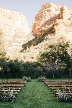 an outdoor ceremony setup with wooden benches and flowers in the foreground, near mountains