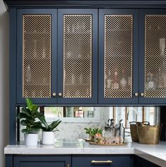 a kitchen with blue cabinets and marble counter tops, gold accents on the doors and drawers