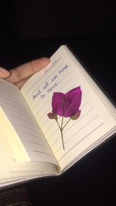 a person holding an open book with a flower on it