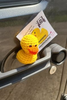 a yellow rubber ducky sitting on the door handle of a car with a parking ticket attached to it