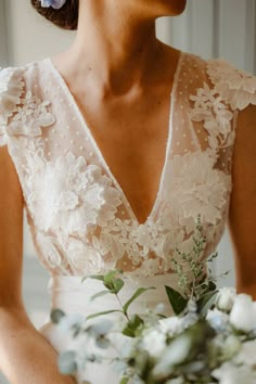 a woman holding a bouquet of flowers in her hand and wearing a white wedding dress