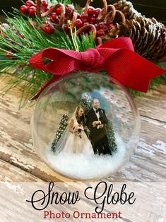 snow globe photo ornament with red ribbon and pine cones